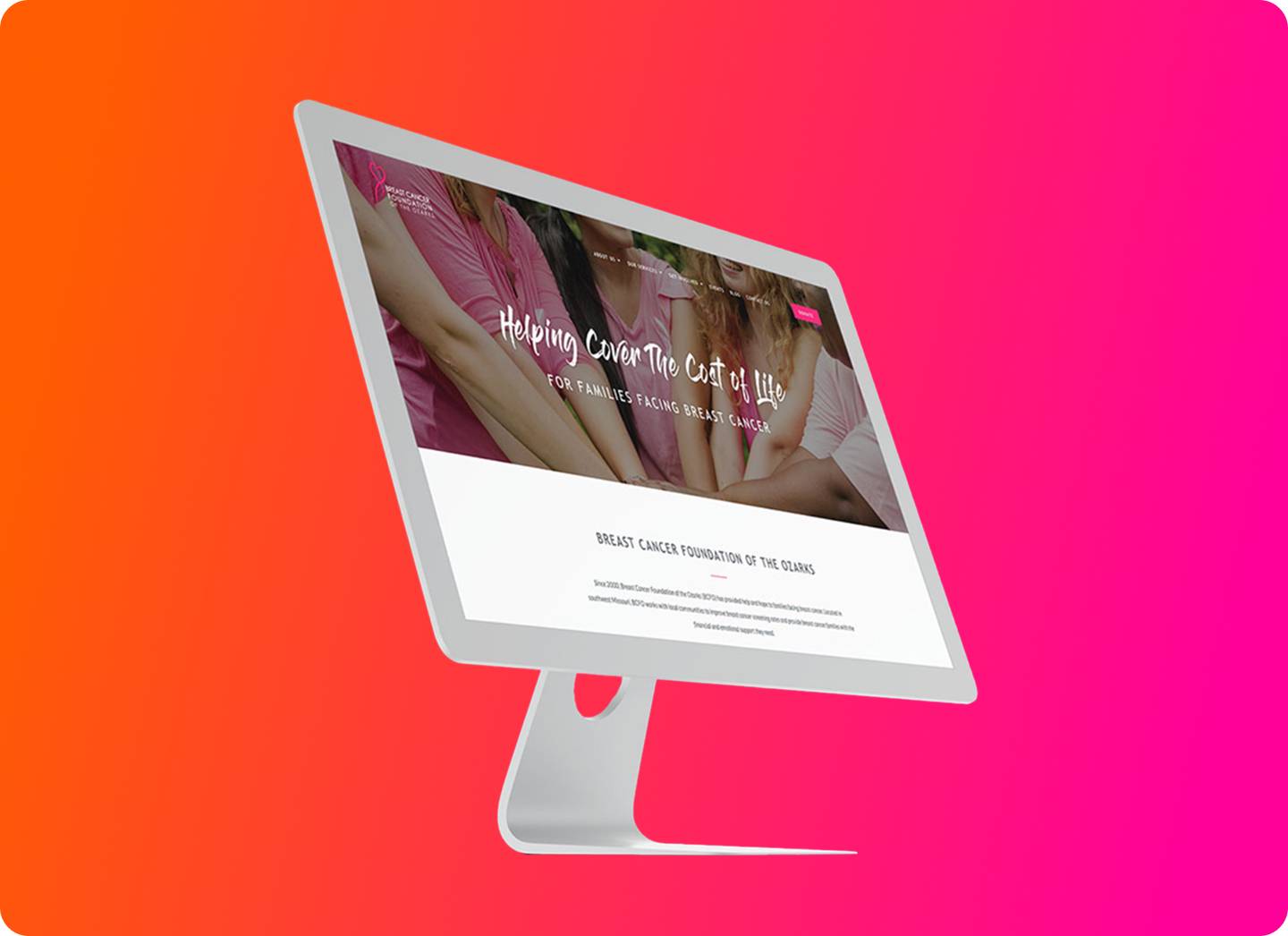 A computer monitor displays a breast cancer foundation website with a pink theme and women linking arms, set against a vibrant pink and orange gradient background.